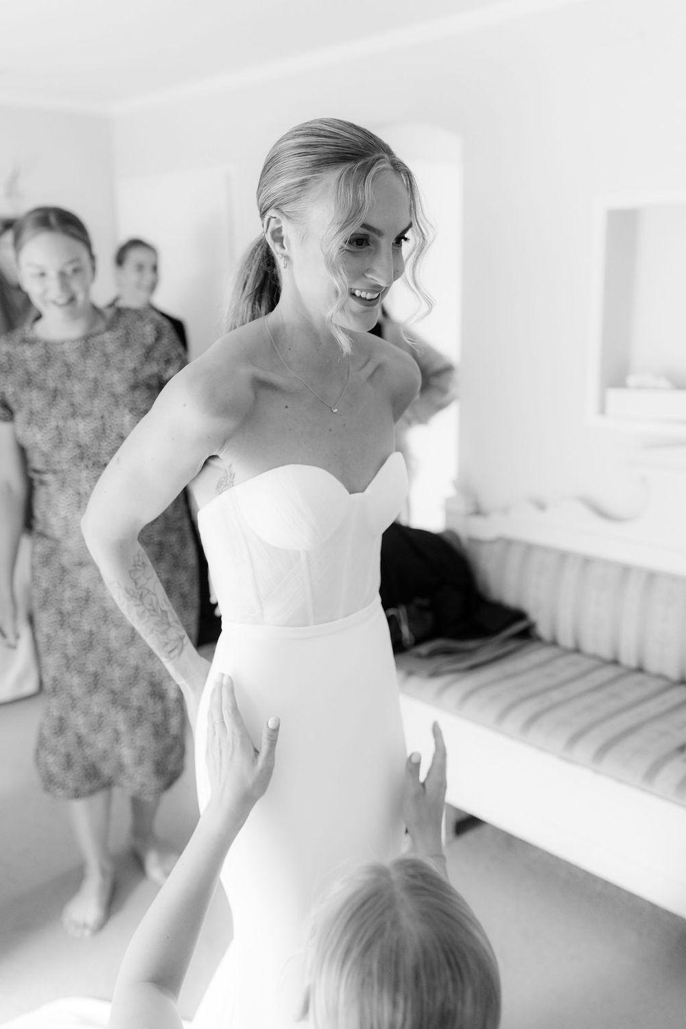 A series of black and white photos showing someone in a white wedding dress during a fitting session.