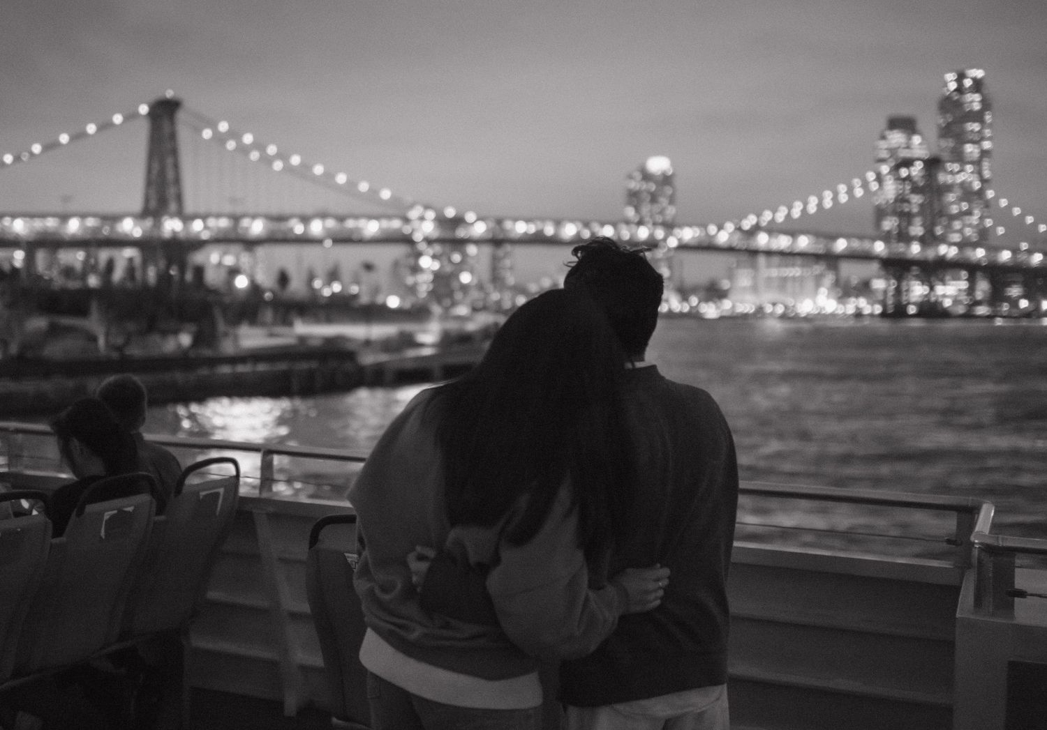 A silhouetted couple enjoys the illuminated city bridge view at night.