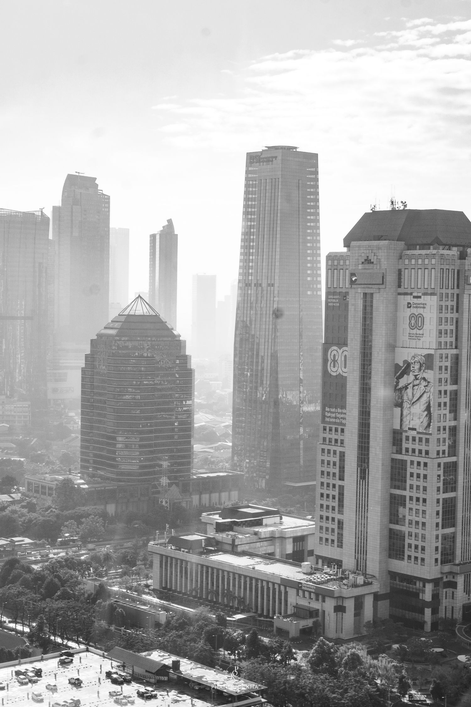 Black and white aerial view of Jakarta city skyline with towering skyscrapers in morning haze.