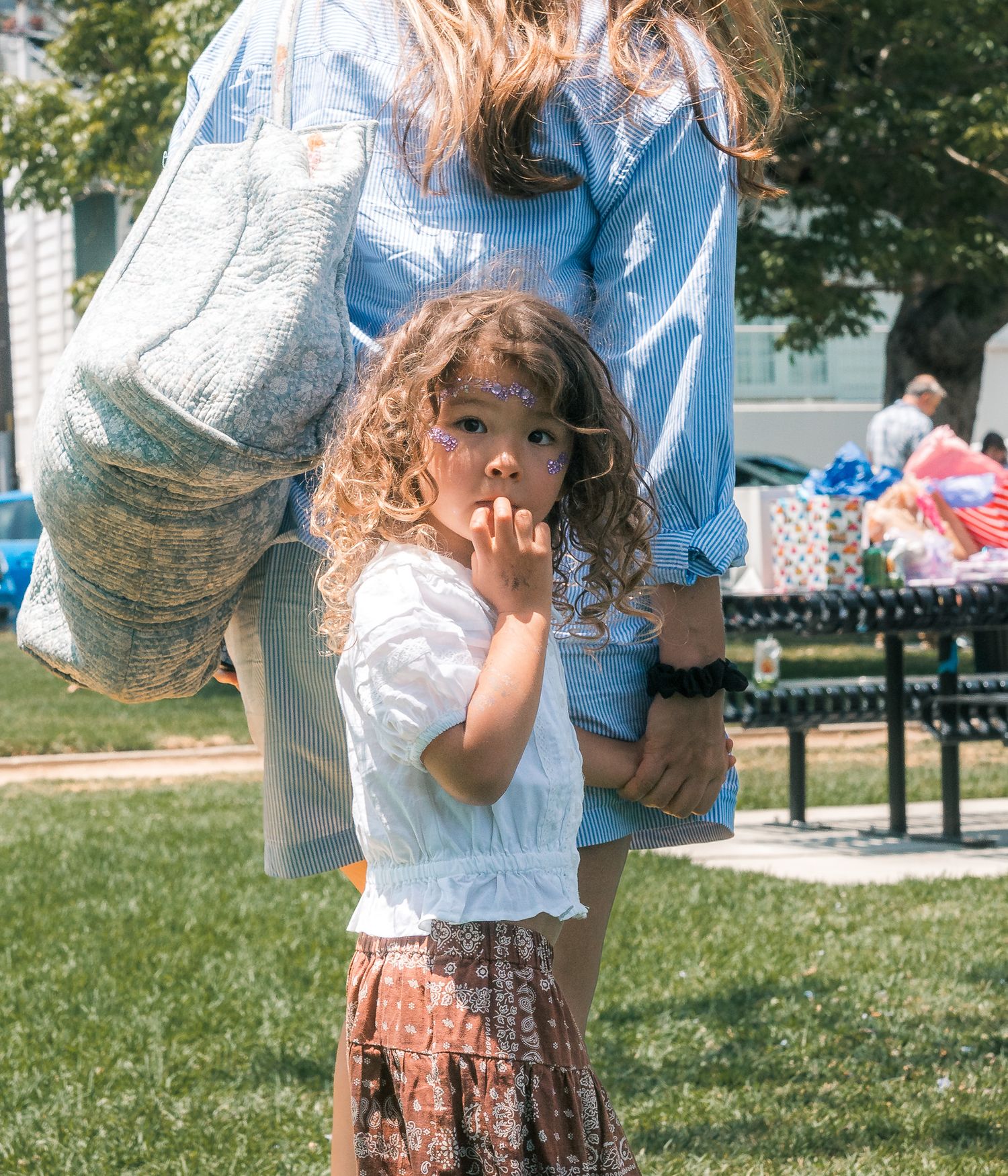 A child wondering why she has to leave the birthday party so early while mom is walking her away. Mariano Alvarez Family Photography