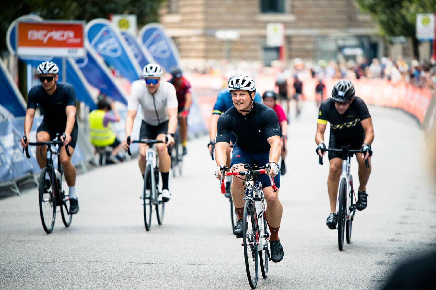 Cyclists racing on road bikes compete in a competitive cycling event on a city street course.
