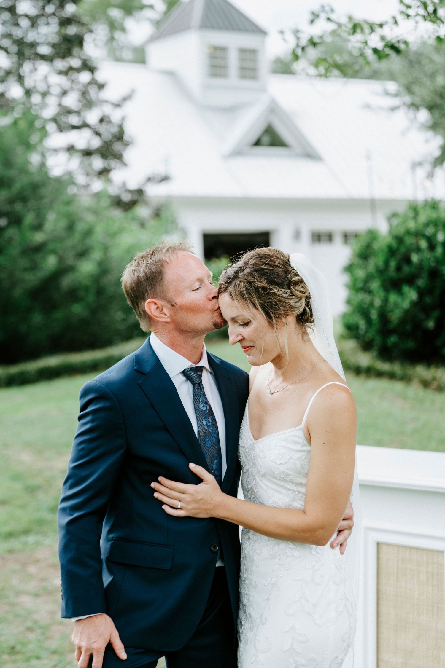 A romantic wedding couple shares an intimate moment together on a white porch railing during their special day.