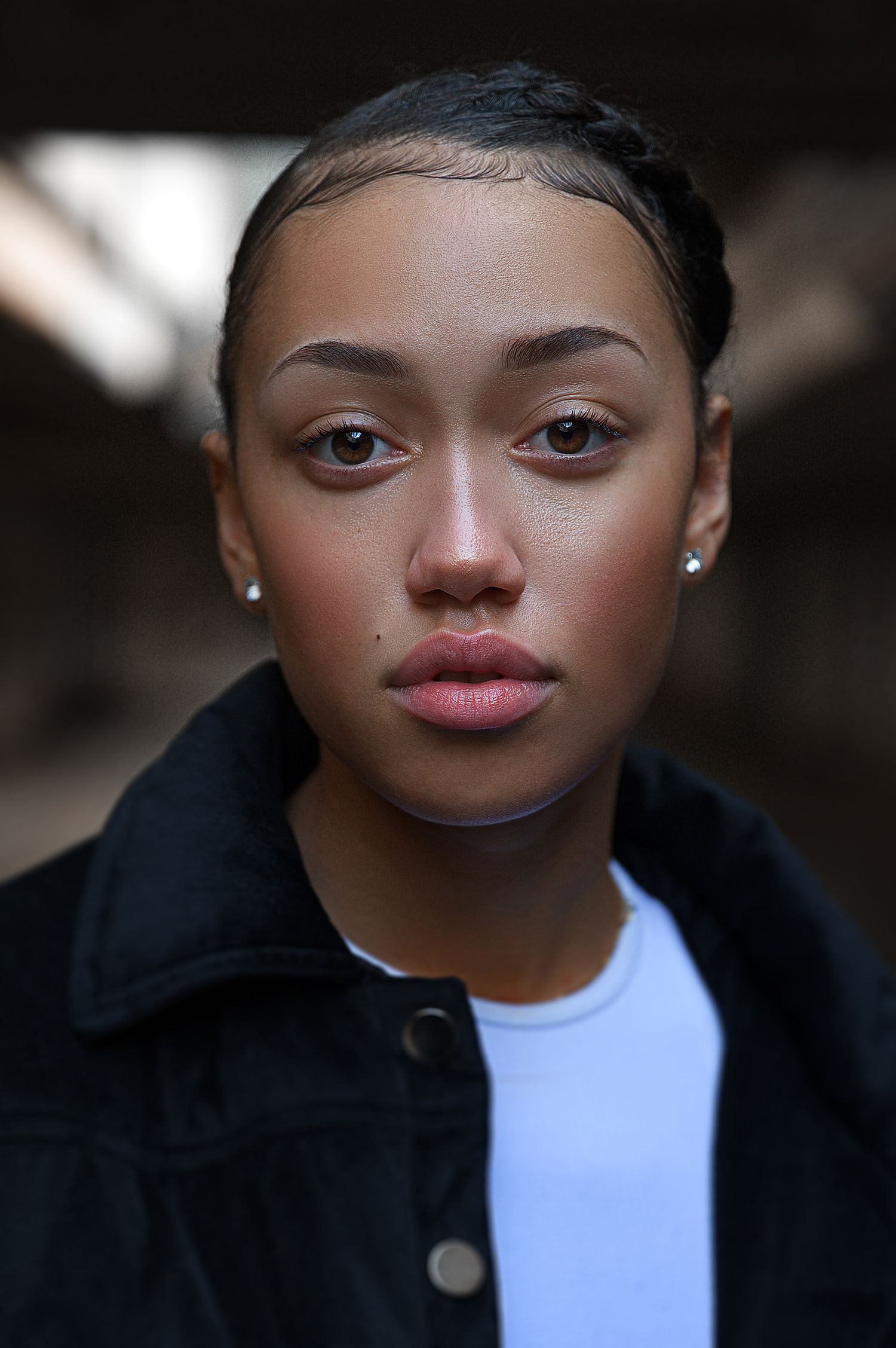 Close up portrait of a person wearing a black jacket and white shirt against a dark background.