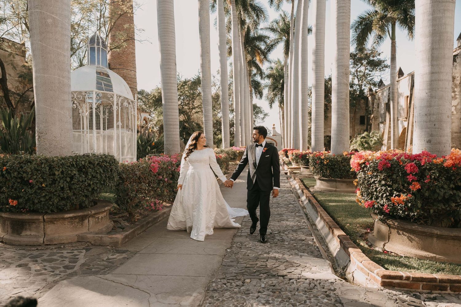 Wedding photos in a stunning colonnade with white pillars and palm trees.