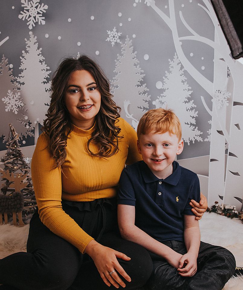 A winter-themed portrait with a yellow sweater and navy polo against a snowy tree backdrop with white decorative snowflakes.