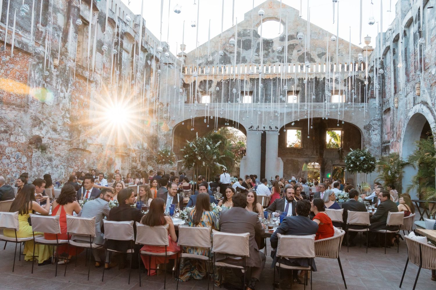 Elegant wedding reception venue with crystal chandeliers and white decor in a grand ballroom setting.