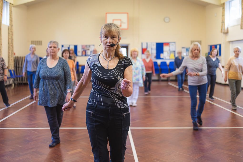 Footsteps Dance School in Letchworth. A group participating in a line dancing exercise class in a bright community centre.