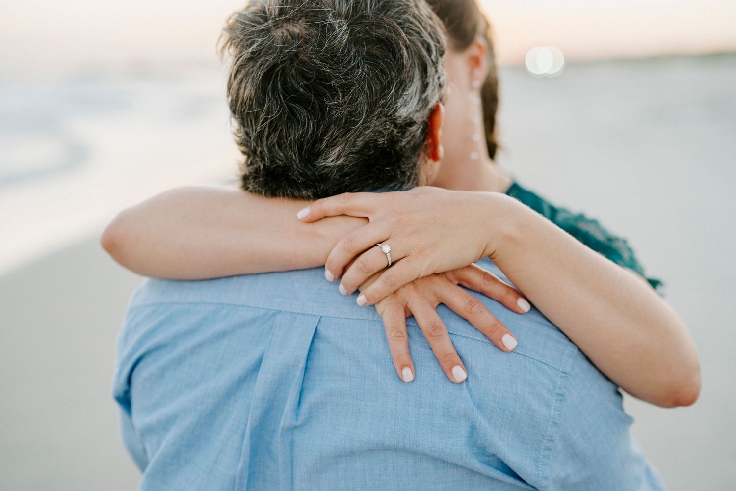 Close up of hands embracing while wearing a light blue shirt.