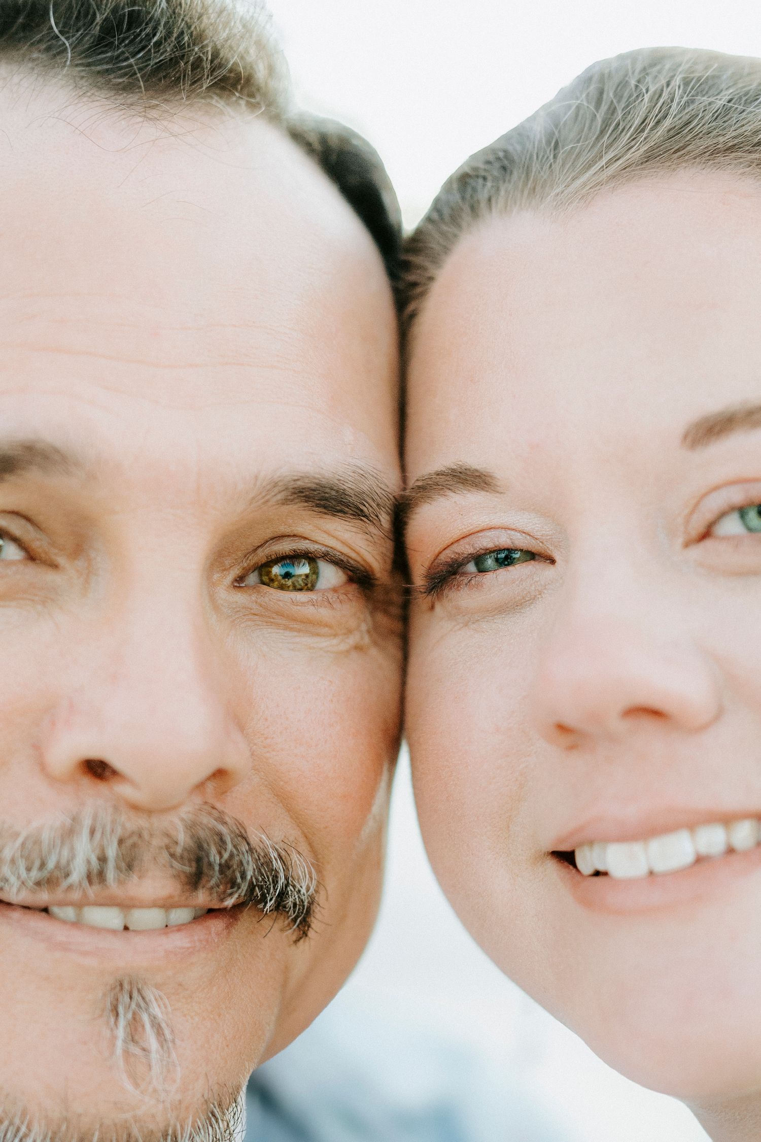 A close-up portrait of a couple with their faces touching and bright smiles.
