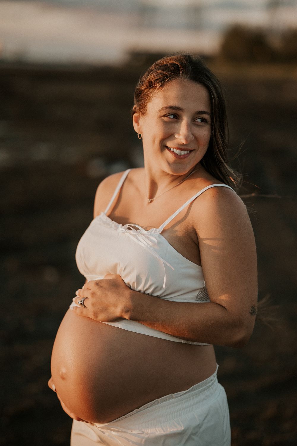 Future maman caressant son ventre en lumière naturelle, moment intime et tendre