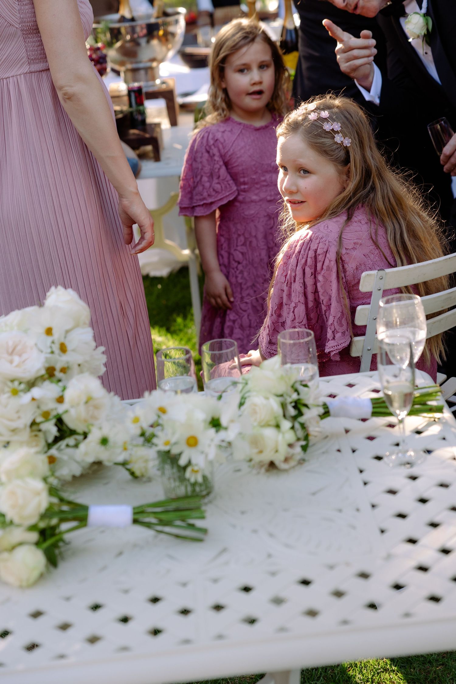 White floral centerpieces decorate a table at an outdoor wedding reception.
