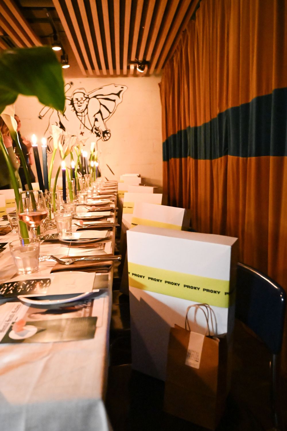 Elegant dining table setup with white linens, glassware, and wooden slat ceiling in an upscale restaurant interior.