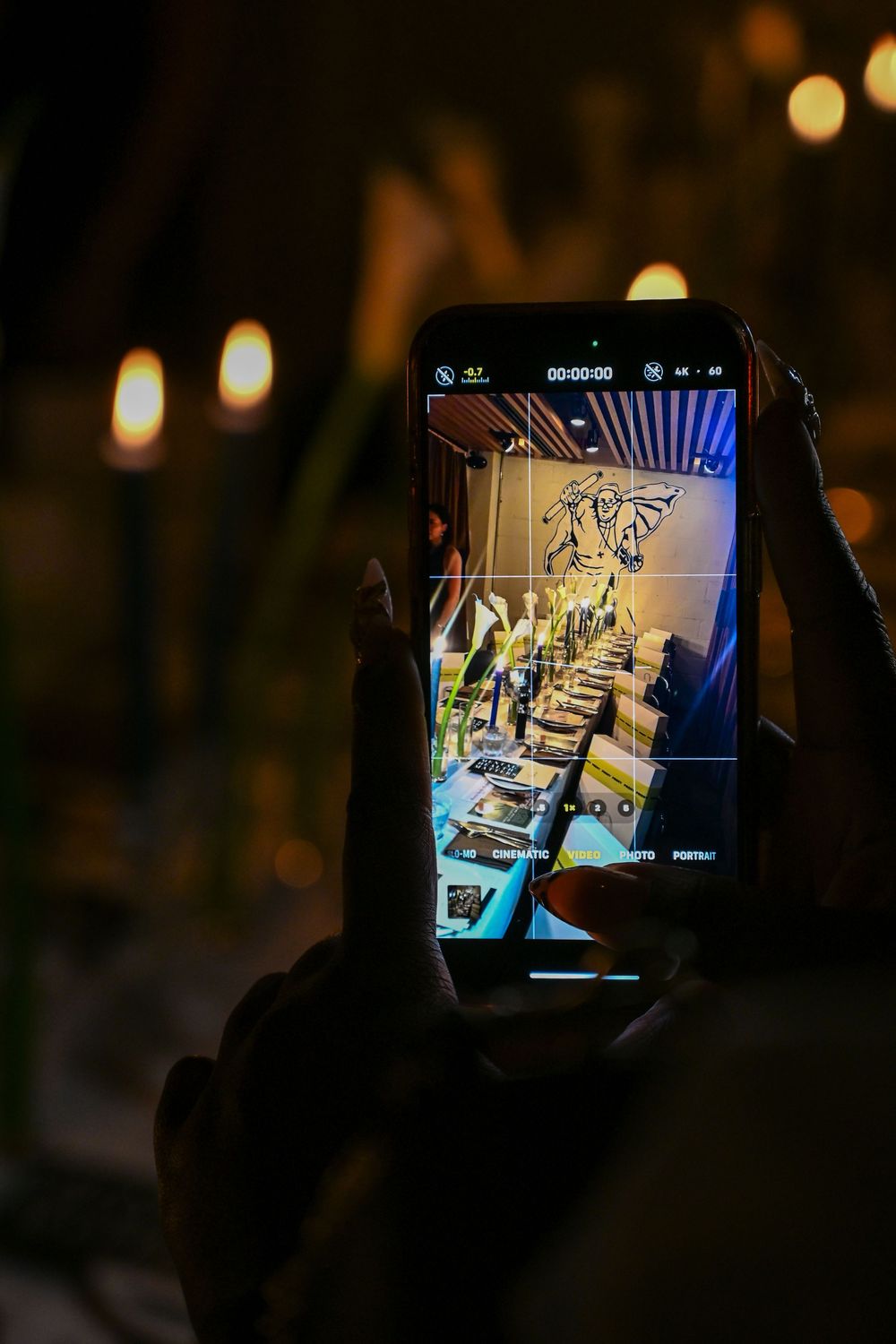 Person holding a mobile device displaying dark screen with blue lighting in a dimly lit environment.