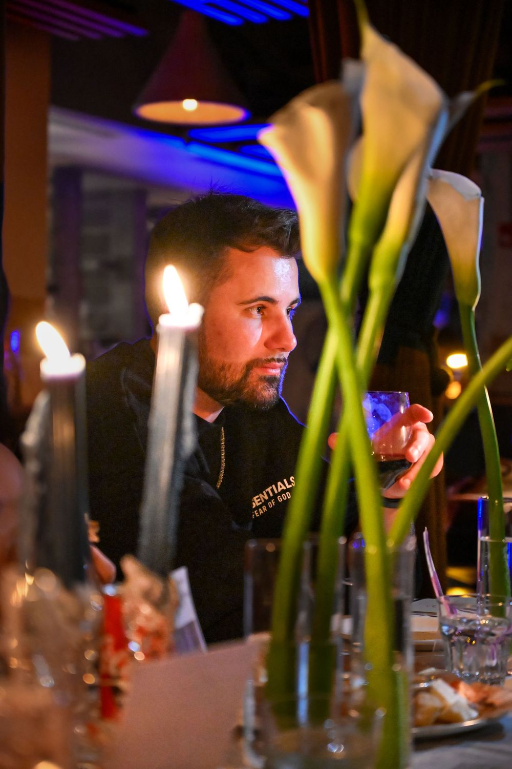 Candlelit dinner setting with tall green calla lily centerpieces and soft blue lighting creating an elegant ambiance.