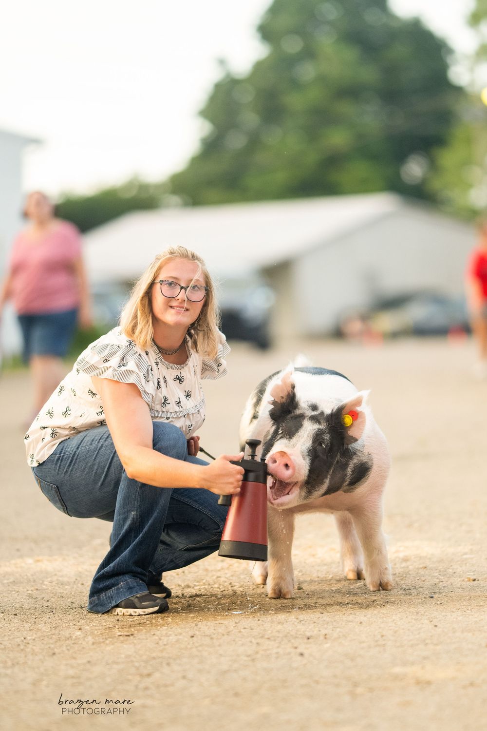 Spotted show pig being trained in dirt arena at county fair.