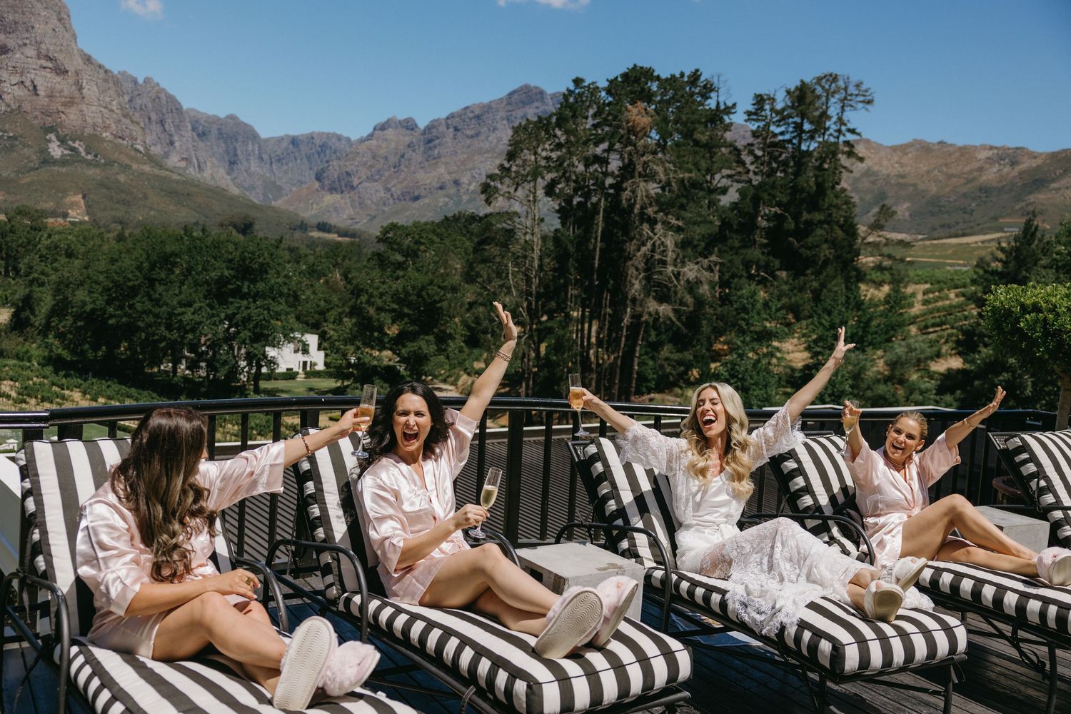 Group lounging on outdoor patio furniture with mountain views and blue sky in the background.