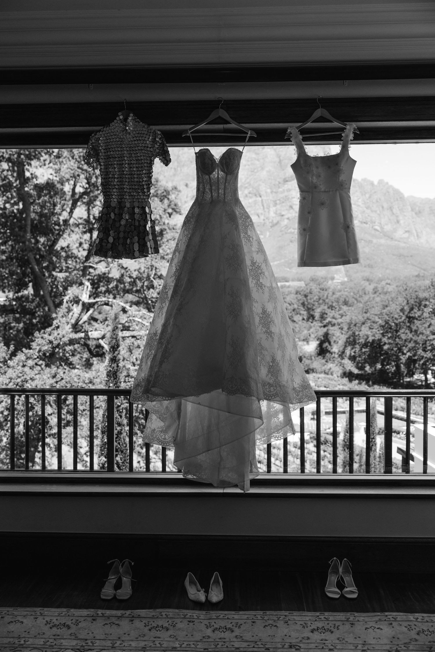 Black and white panoramic view of dresses hanging on a clothesline against a railing with a scenic background.