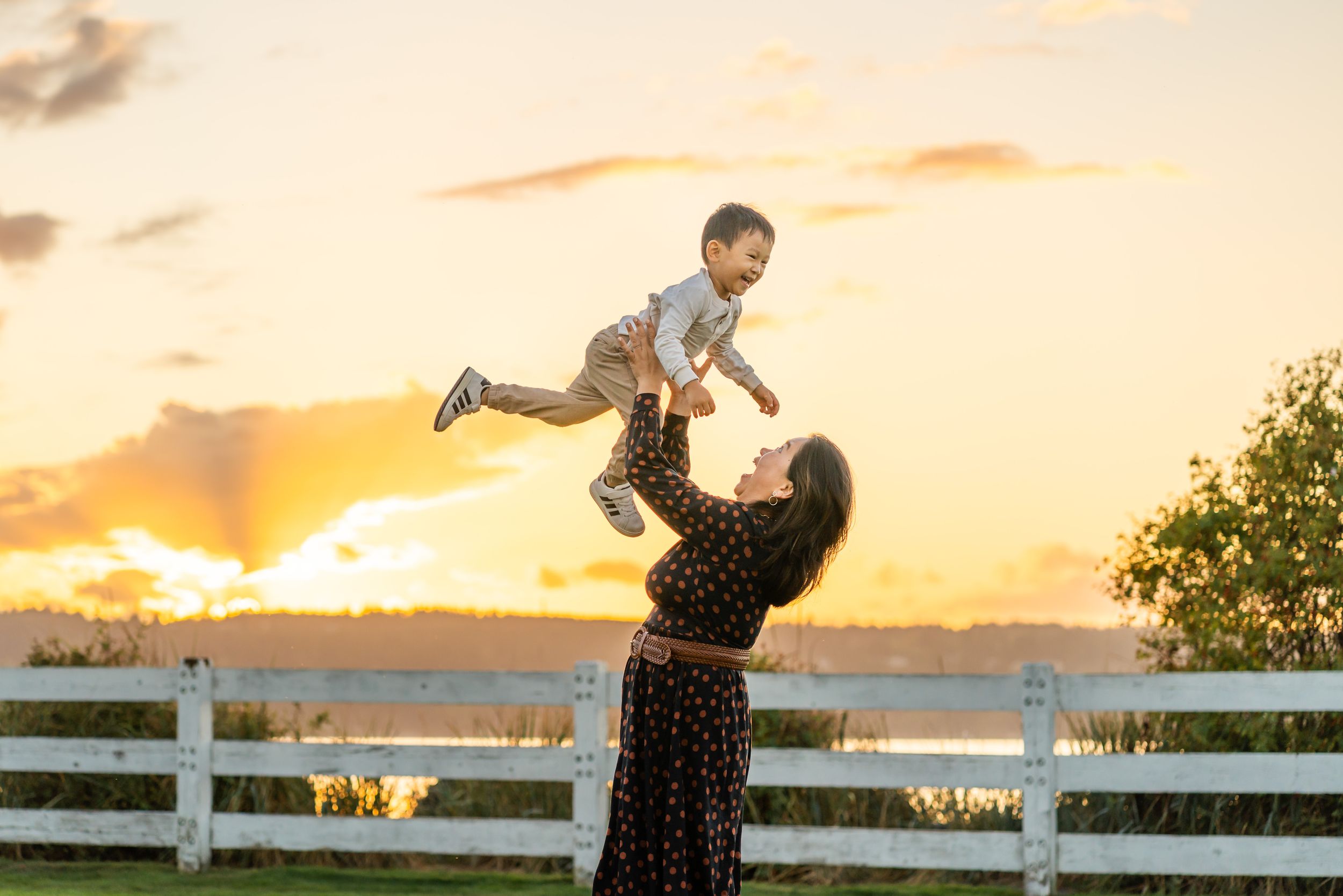 Mom throws son into air at sunset in Mukilteo.