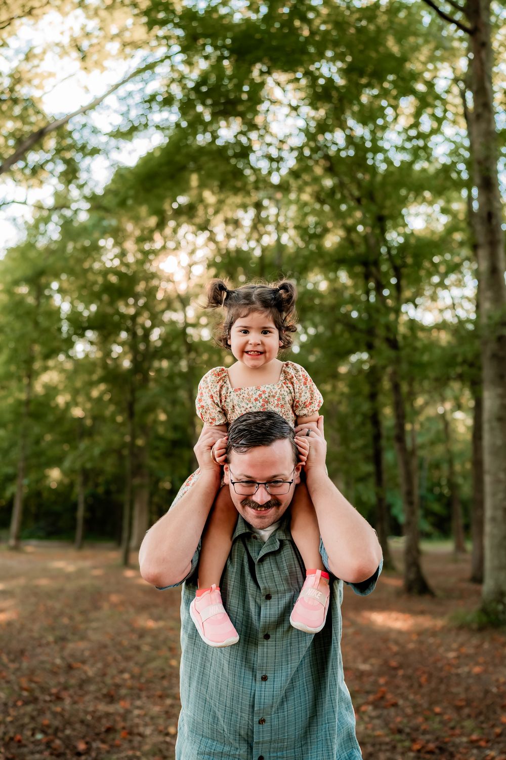 A joyful moment shared between parent and child playing together in a wooded setting at sunset.