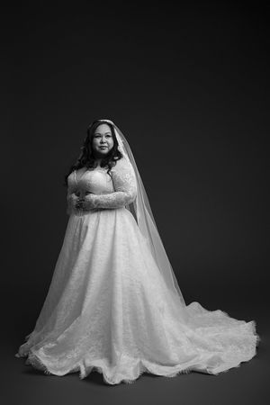 A black and white portrait series showing a bride in a flowing lace wedding gown against a dark background.