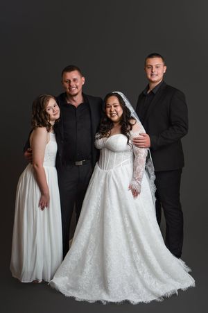Wedding party poses together in black and white formal attire showing the elegant lace details of bridal gowns.