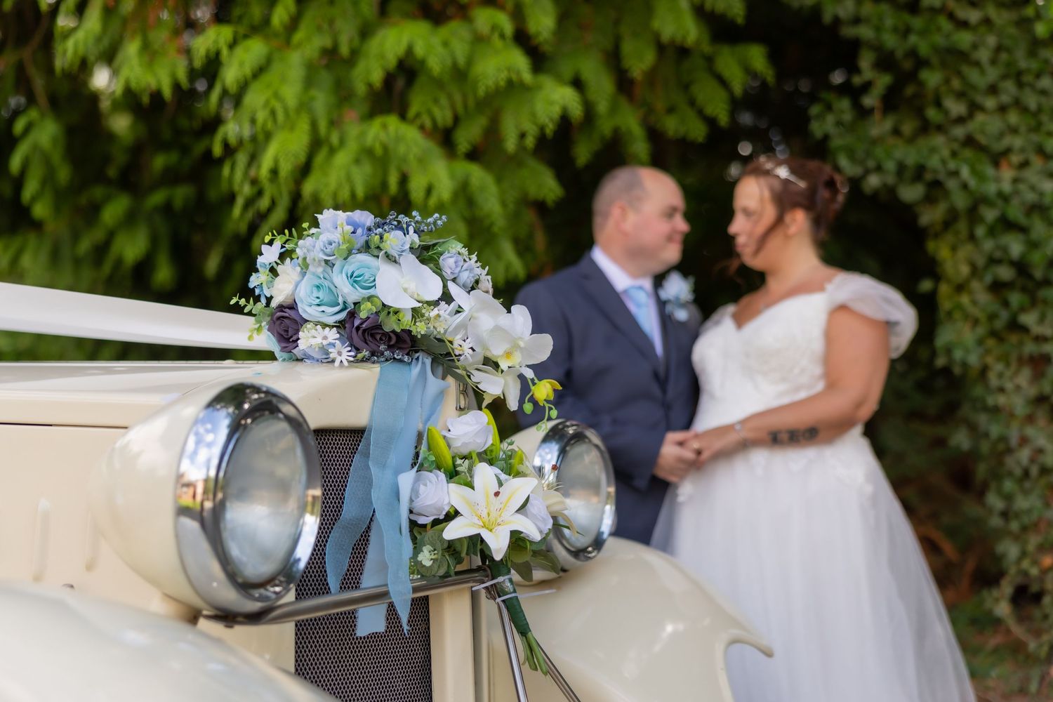 A romantic wedding couple embraces in a garden setting with elegant floral bouquets and vintage decor.