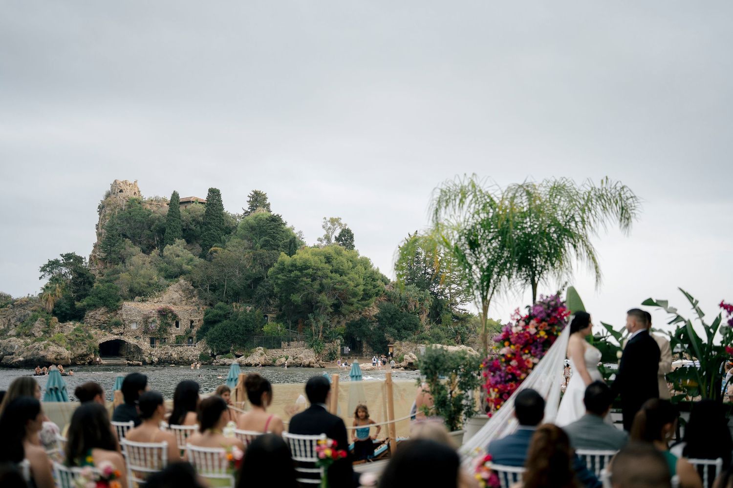 A panoramic view of an outdoor wedding ceremony setup with mountain scenery and palm trees in the background.