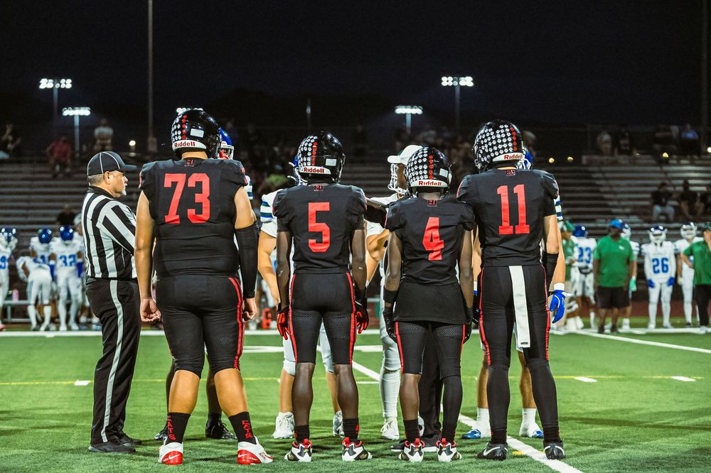 Football players mid field before the game, talking to the refs