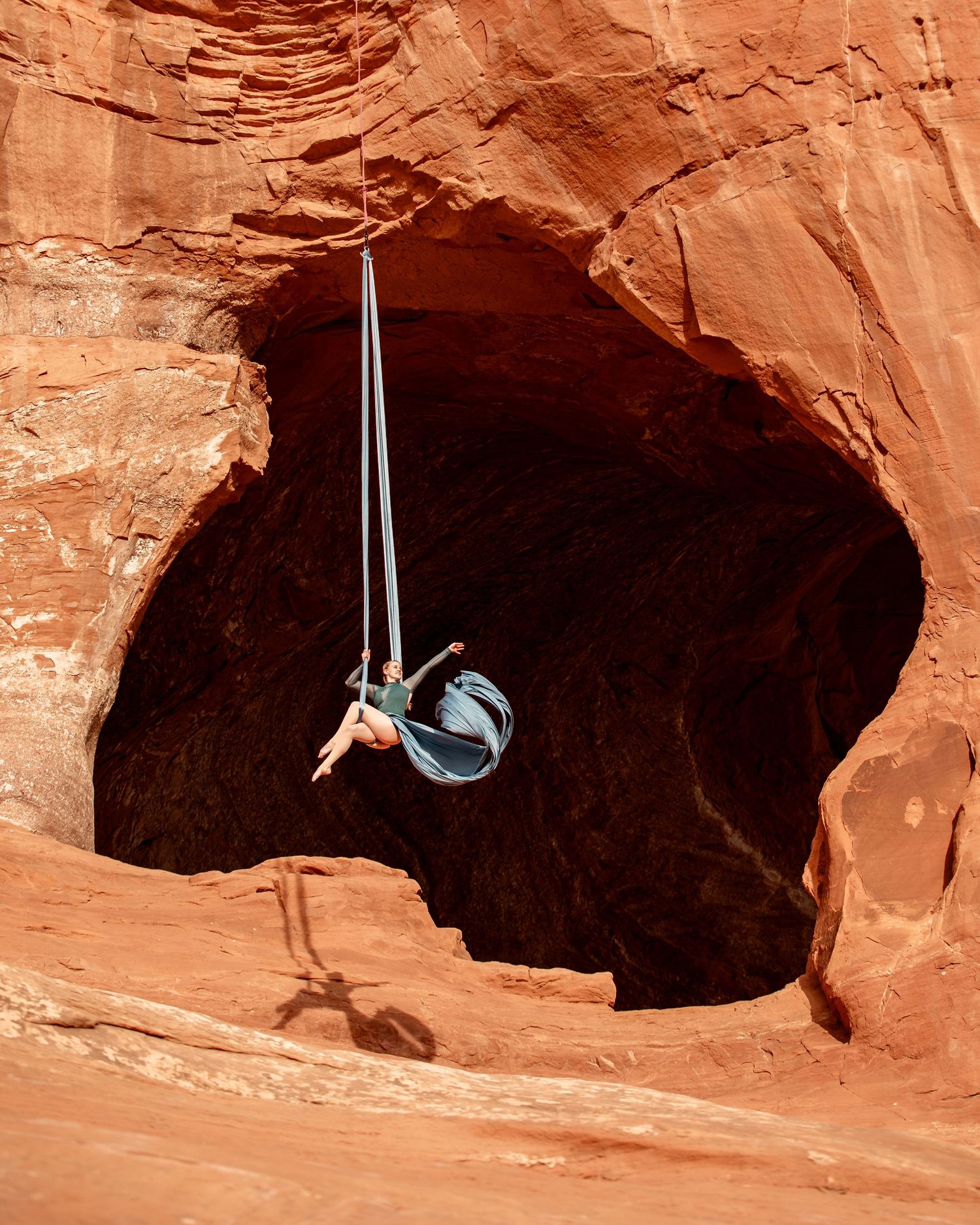Aerialist posed on silks set against a Utah red rock arch; crisp aerial arts portrait mixing natural tones with technical form.