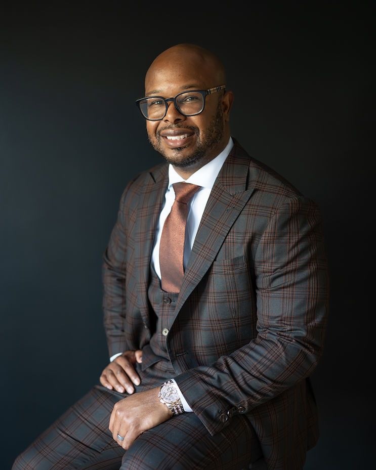 Professional man in plaid suit and tie smiling confidently for a formal business portrait photo.