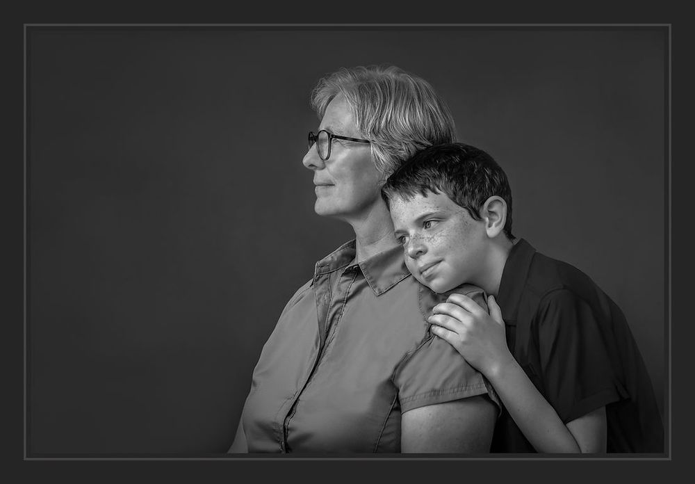 Black and white portrait of an older woman and young boy posing together in a studio.