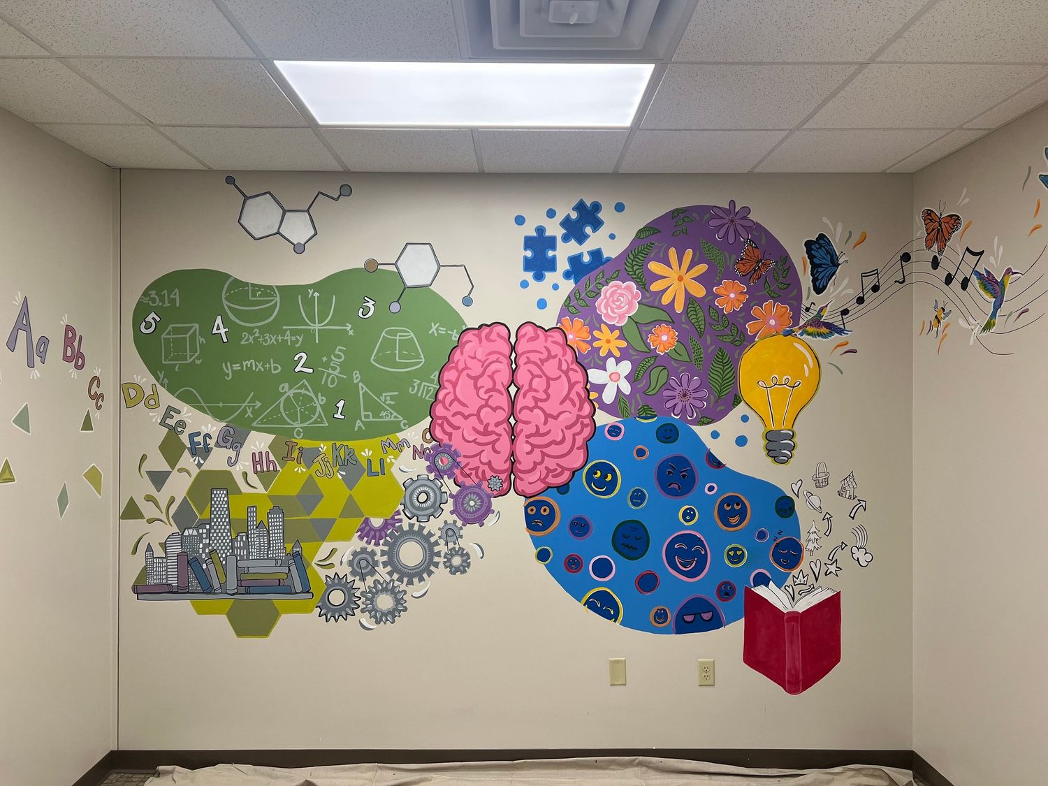 Colorful wall mural featuring puzzle pieces, gears, and a brain design decorates a classroom or educational space.