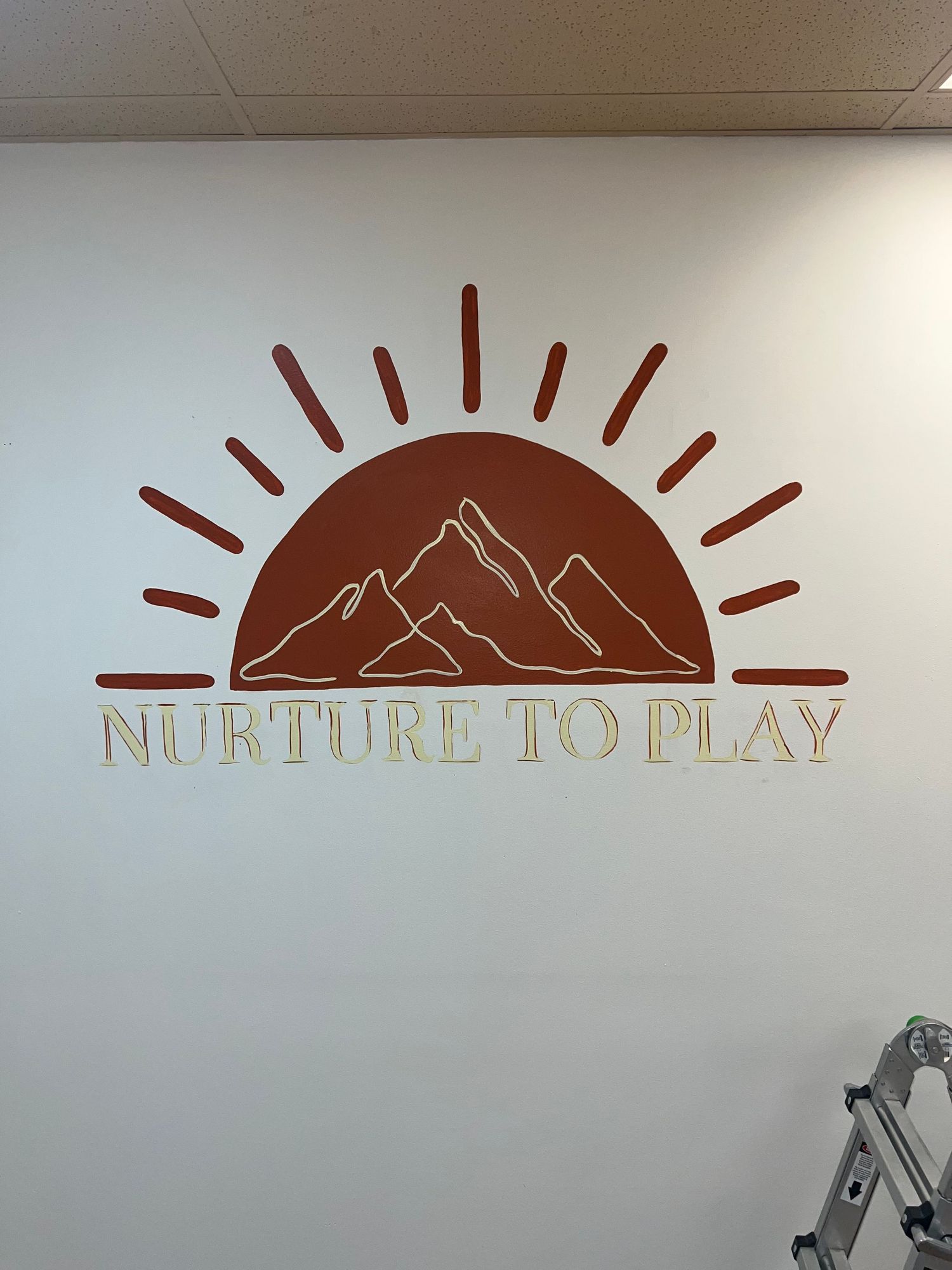 A series of minimalist wall decals showing mountain and sun designs with the text 'NURTURE TO PLAY' in neutral colors.