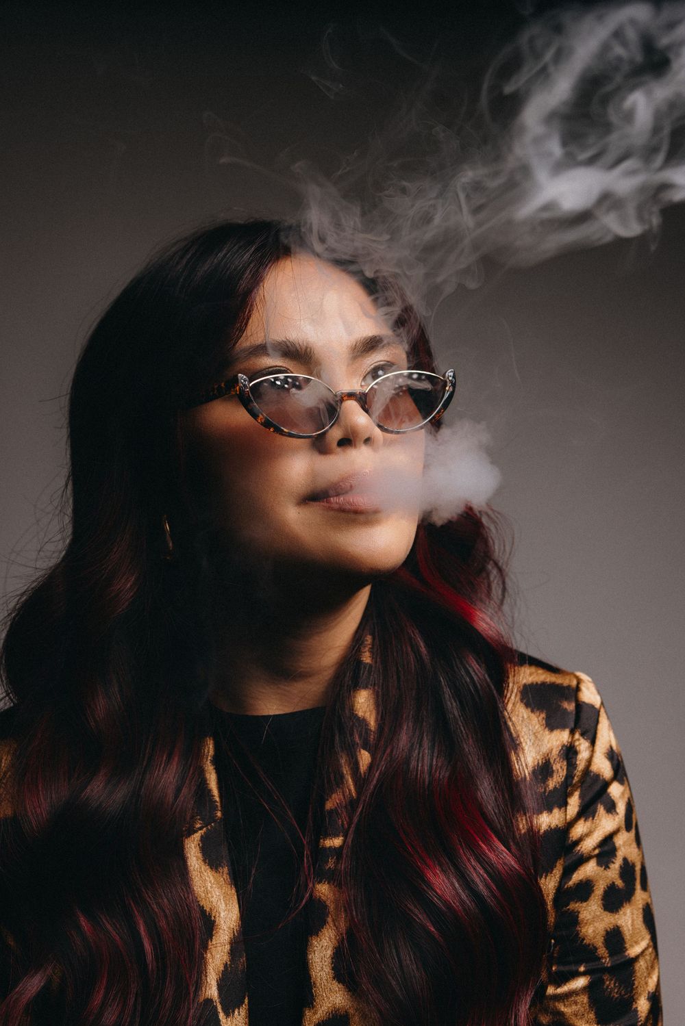 Artistic smoke photography with leopard print jacket and glasses.