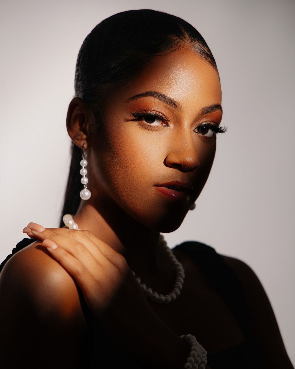 Dramatic beauty portrait with sparkling earrings and glamorous makeup in moody lighting.