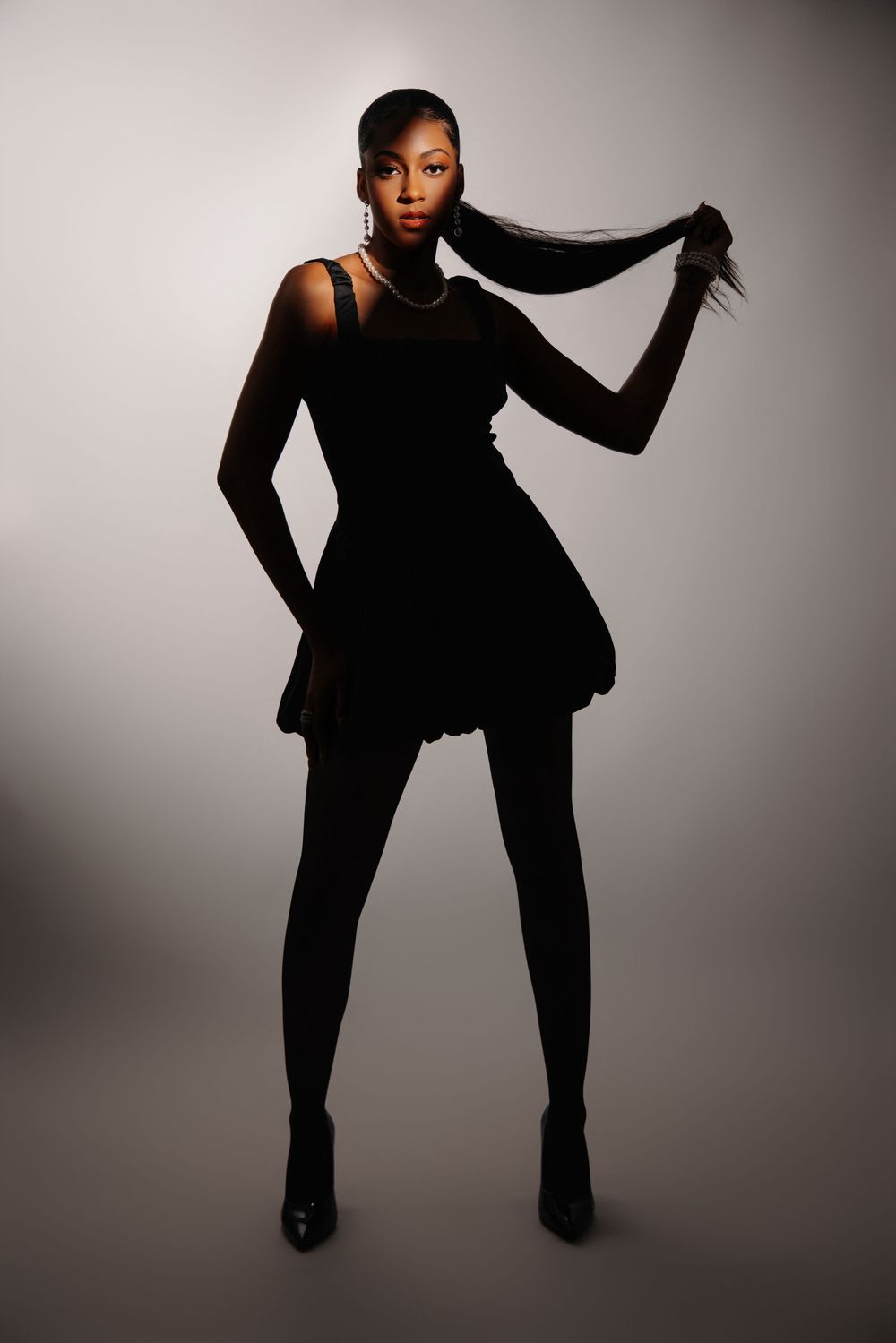 Silhouetted figure in black outfit striking dynamic poses against light background.