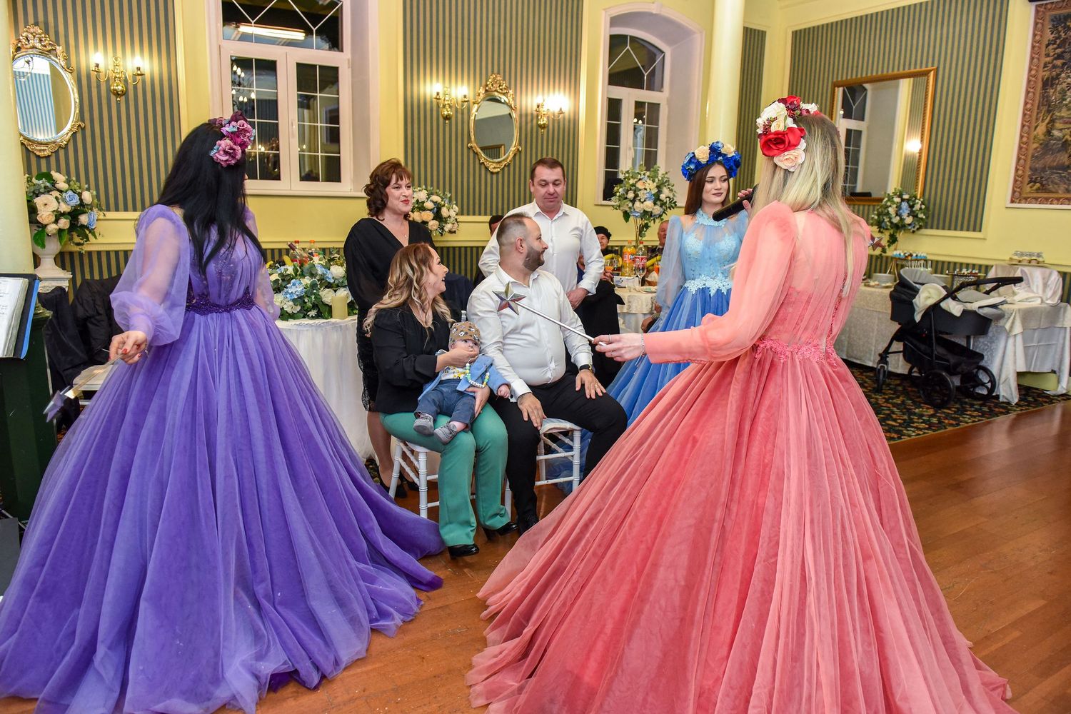 Elegant ballgowns in vibrant pink and purple colors fill a grand ballroom during a formal dance event.