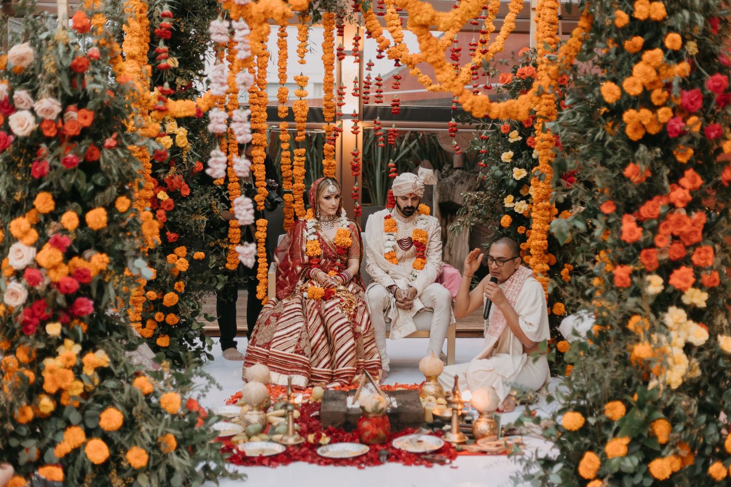 Vibrant orange and red floral arrangements create a stunning outdoor wedding ceremony backdrop.