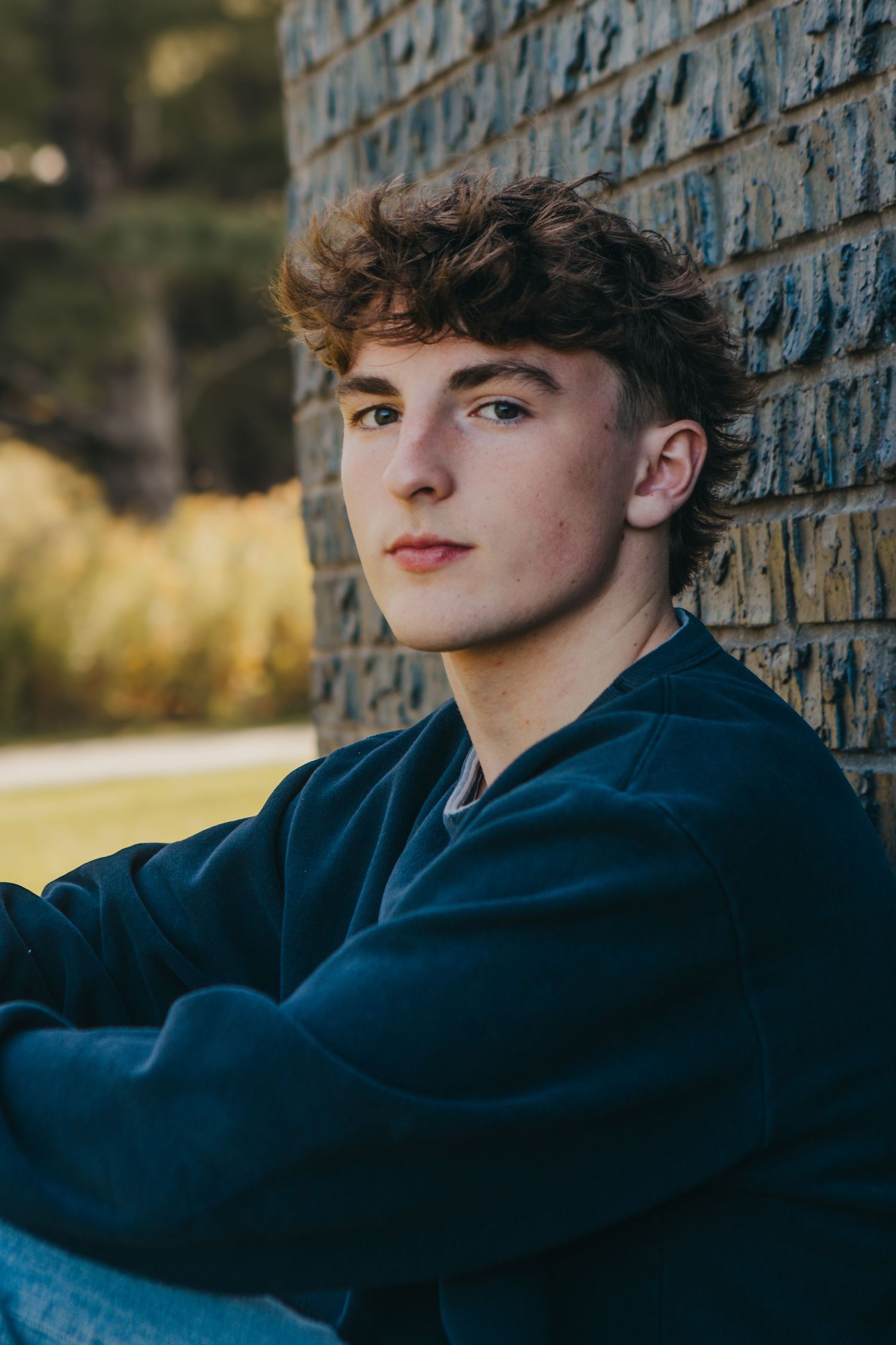 Portrait series against textured brick wall in natural lighting.