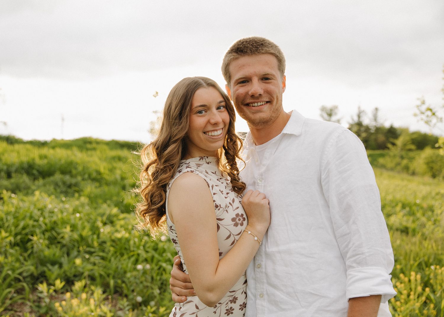 Romantic couple touching foreheads and smiling outdoors among green trees in a tender intimate moment.