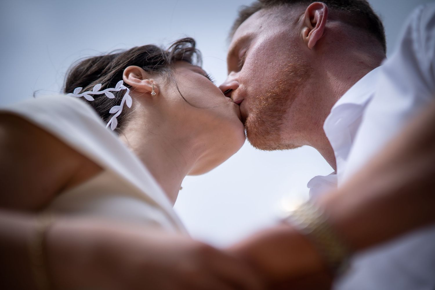 A romantic couple shares a tender kiss in a soft, intimate close-up photograph.
