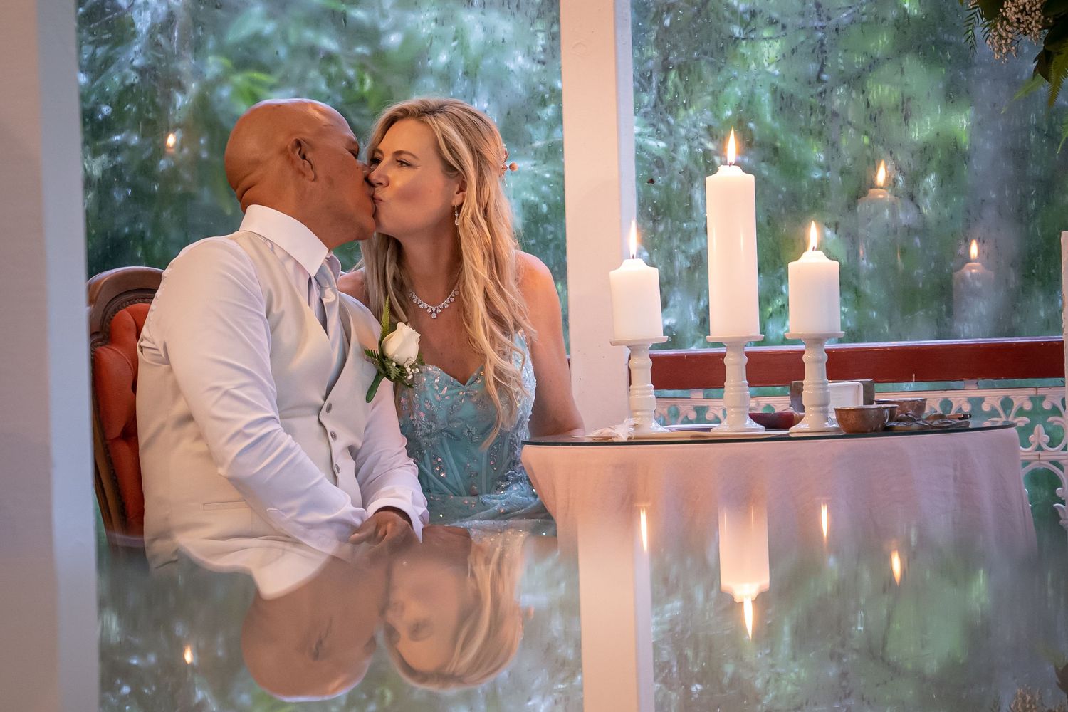 Romantic candlelit dinner scene with white candles glowing on reflective table surface in elegant setting.