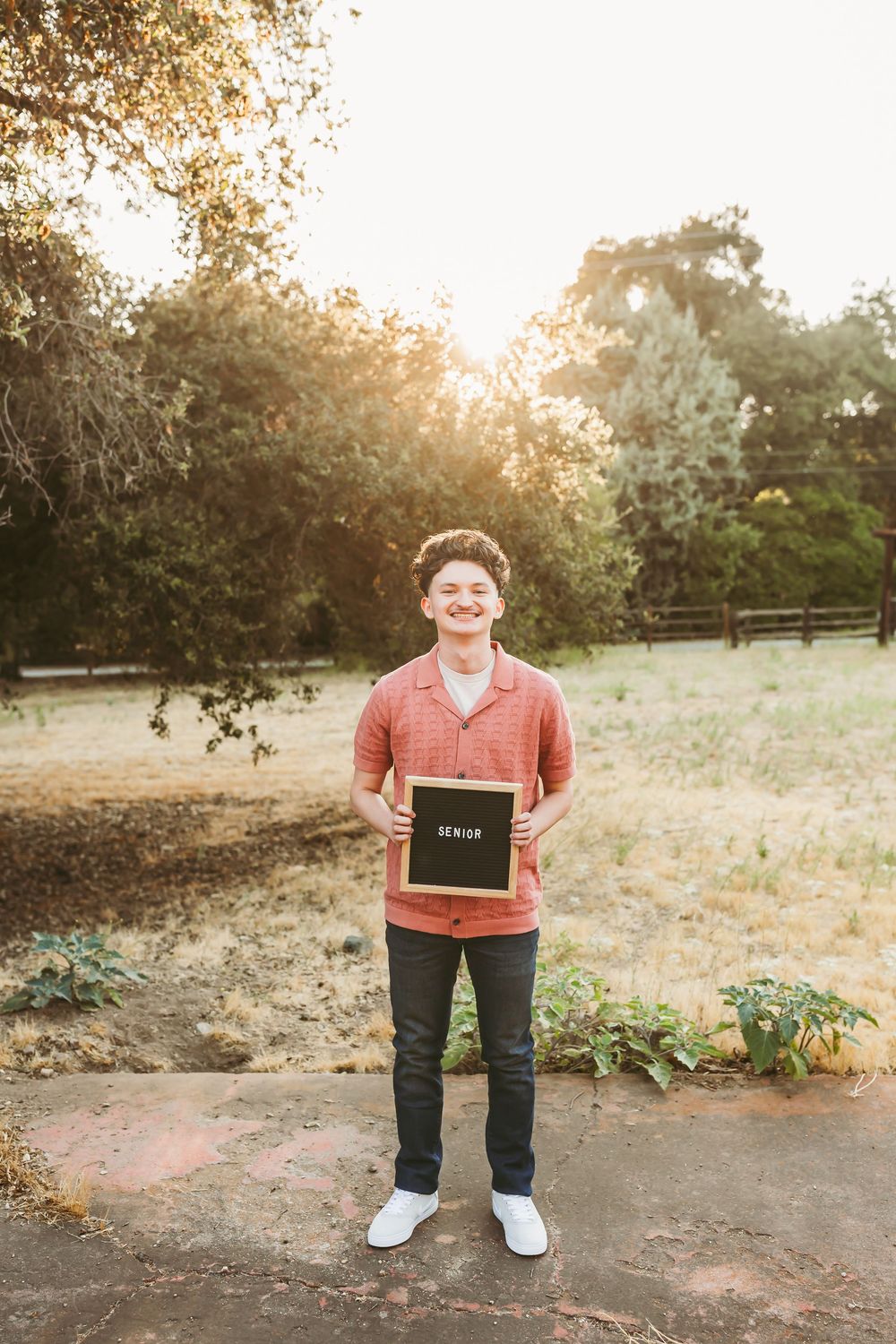 Sunset portrait session in a rustic outdoor setting with golden light filtering through trees.