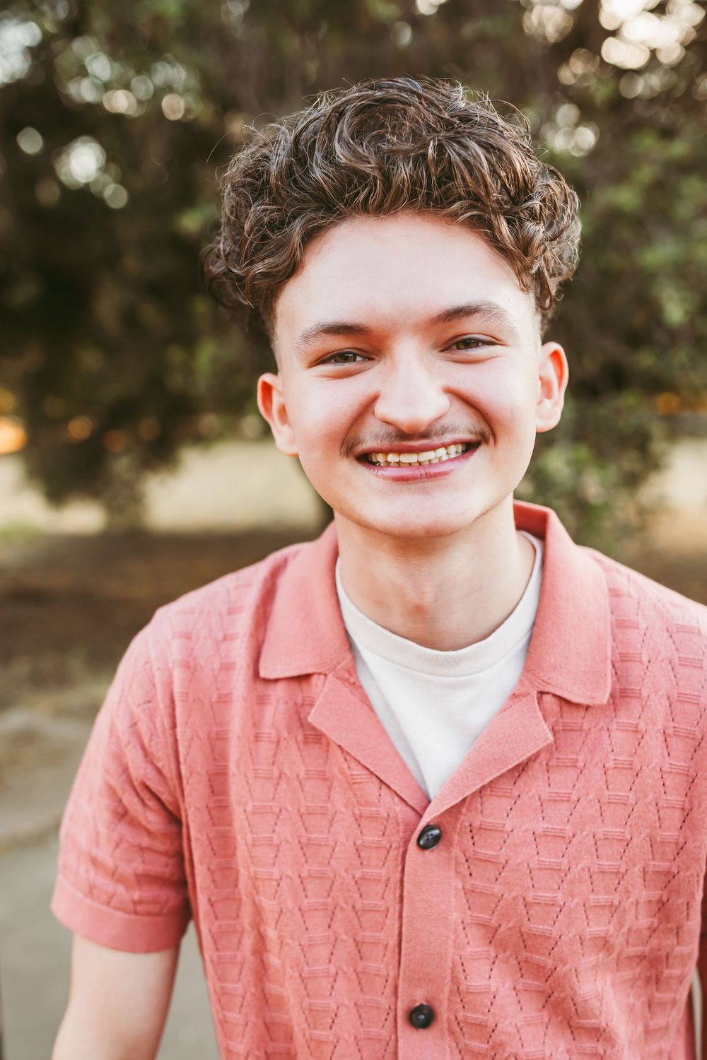 A series of four outdoor portrait shots showing someone wearing a coral pink textured shirt and white undershirt.