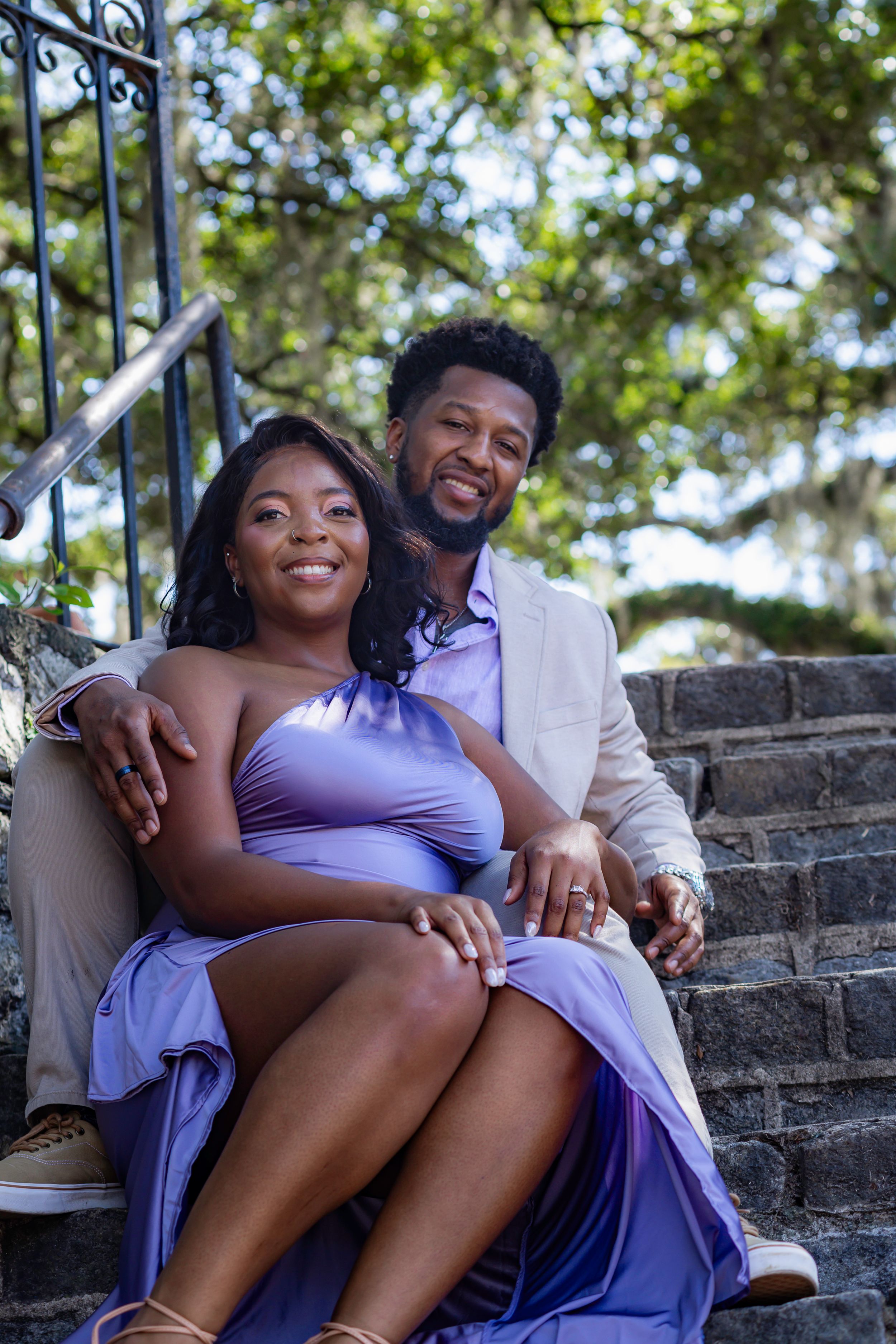 A couple shares a tender moment while sitting together on stone steps outdoors.