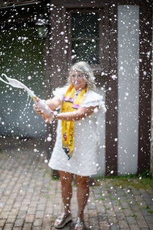 Someone in a white dress and yellow scarf splashes water on a rainy day with droplets flying through the air.