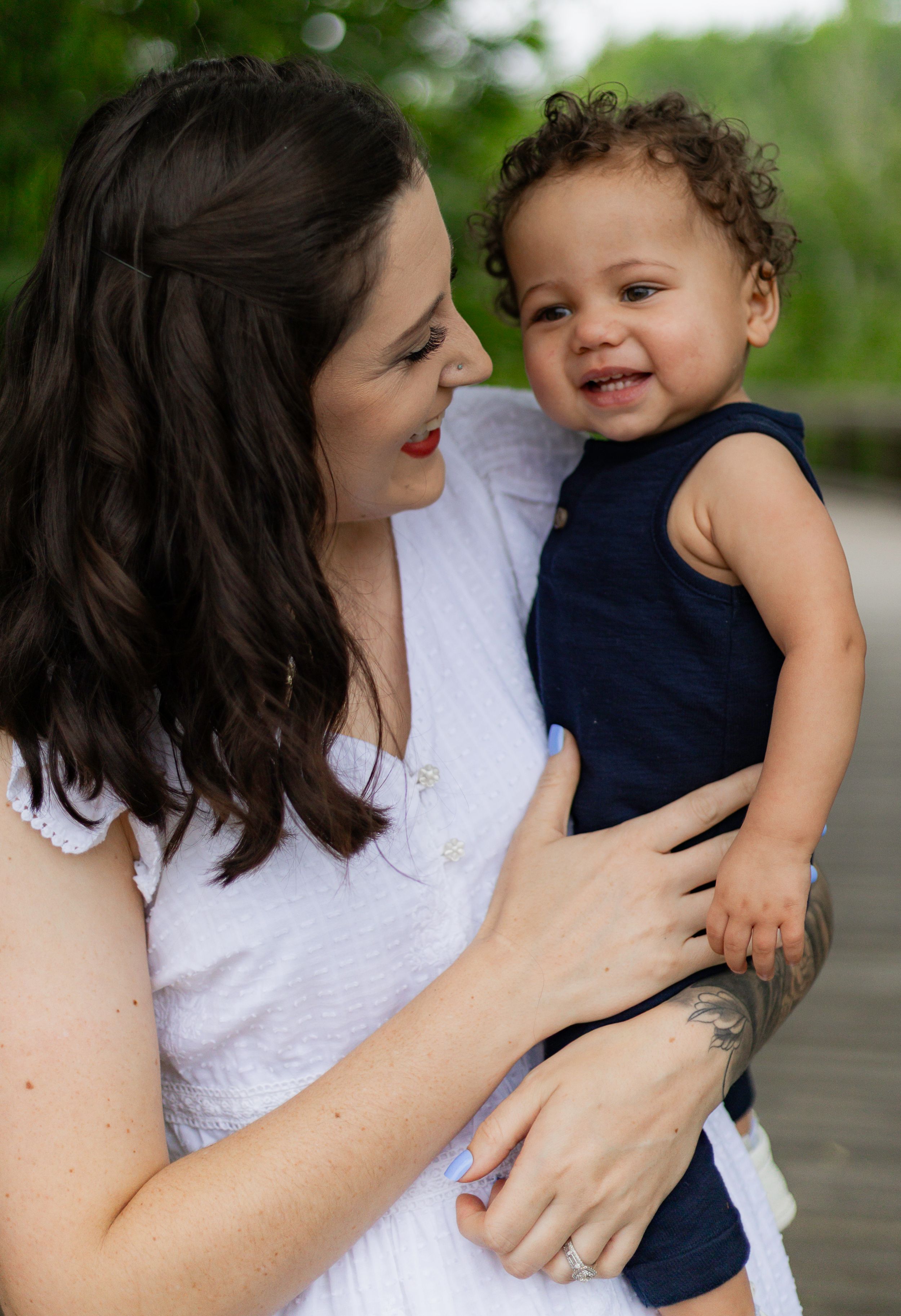 Tender moment between parent and child embracing against green outdoor background.