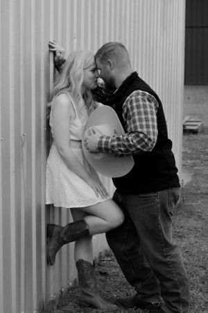 Sweet black and white photo series showing couple sharing romantic moments against corrugated wall.