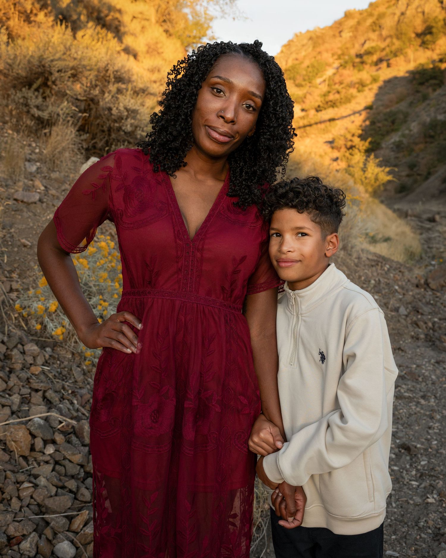 Two people pose together against a golden rocky landscape in warm sunset lighting.