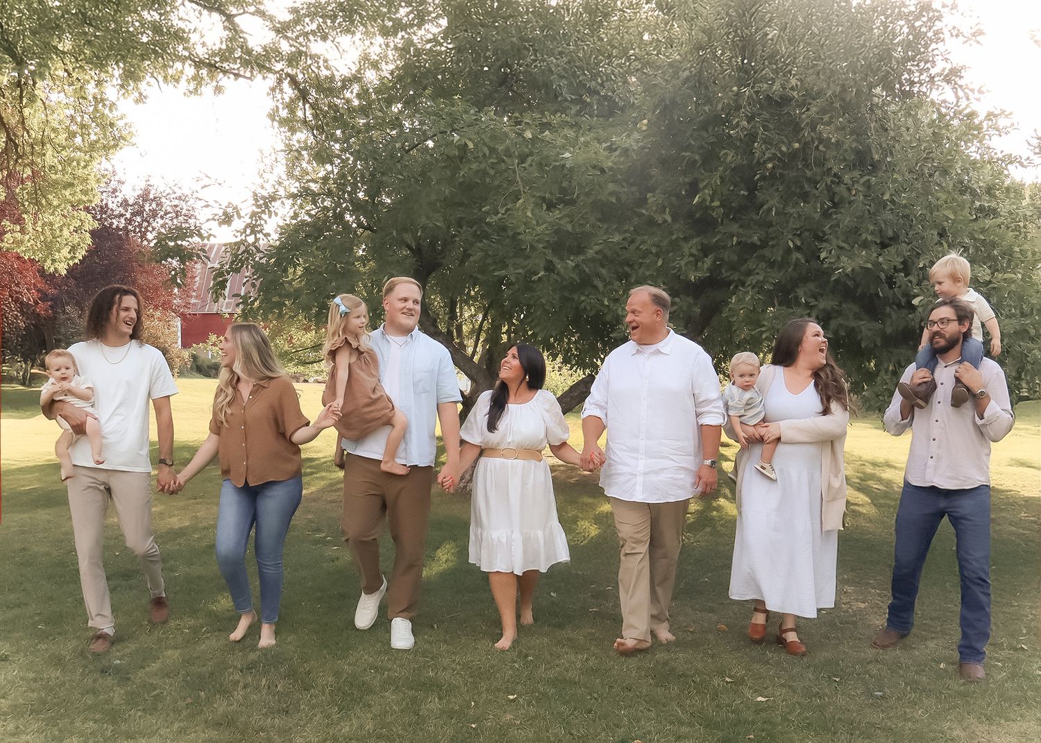 Extended family walking together outdoors holding hands and smiling during a summer family portrait session in Ogden Valley ,Utah